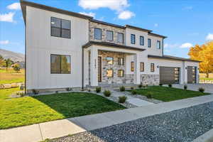 View of front of home with a garage and a front lawn