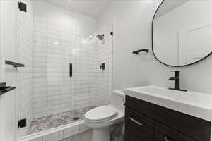 Bathroom featuring an enclosed shower, vanity, and toilet