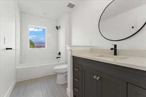 Full bathroom featuring tiled shower / bath, vanity, toilet, and tile flooring