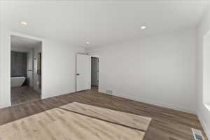 Unfurnished bedroom featuring hardwood / wood-style floors and ensuite bath