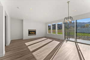 Unfurnished living room with a notable chandelier, a mountain view, and hardwood / wood-style flooring