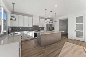 Kitchen featuring a center island, hanging light fixtures, appliances with stainless steel finishes, premium range hood, and wood-type flooring