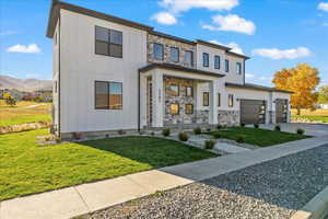 View of front of home with a front lawn, a garage, and a mountain view