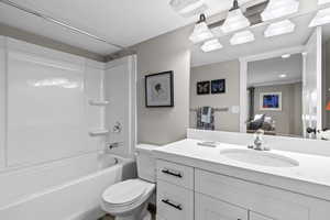 Full bathroom featuring washtub / shower combination, vanity with extensive cabinet space, toilet, and ornamental molding