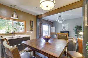 Dining space featuring beam ceiling, sink, and brick wall