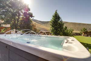 View of swim spa with a yard and a mountain view