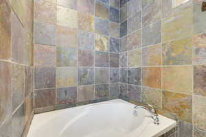 Master Bathroom featuring a bathing tub and tile walls