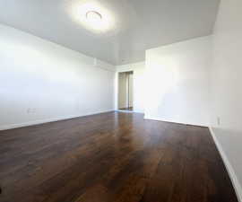 Spare room with a textured ceiling and dark hardwood / wood-style floors