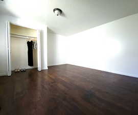 Unfurnished bedroom featuring a closet, a textured ceiling, and dark hardwood / wood-style floors