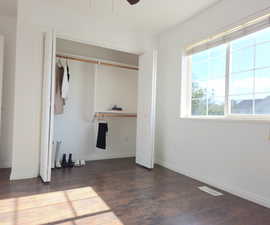 Unfurnished bedroom with a closet, ceiling fan, and dark hardwood / wood-style flooring