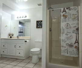 Bathroom featuring walk in shower, tile flooring, toilet, and large vanity