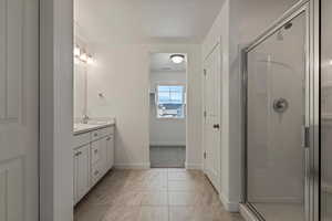 Bathroom featuring a shower with shower door, tile flooring, double vanity, and a textured ceiling