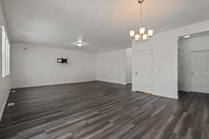 Empty room featuring an inviting chandelier and dark hardwood / wood-style flooring