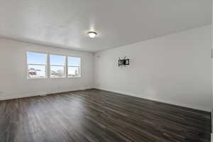 Empty room featuring a textured ceiling and dark wood-type flooring