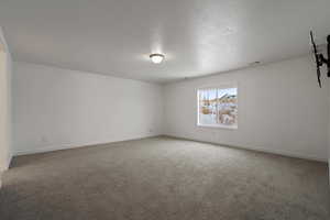 Empty room with a textured ceiling and carpet flooring