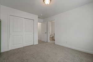 Unfurnished bedroom with ensuite bathroom, a closet, and carpet floors