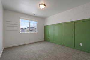 Empty room with a textured ceiling and carpet flooring