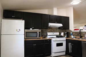 Kitchen featuring stainless steel appliances, vaulted ceiling, sink, and backsplash