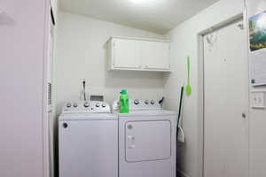 Washroom with washer hookup, washer and clothes dryer, crown molding, and cabinets