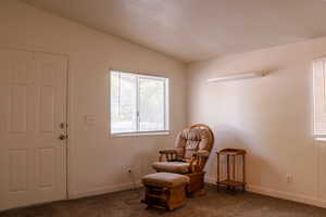 Living area with carpet flooring and vaulted ceiling