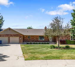 Single story home with a garage and a front lawn