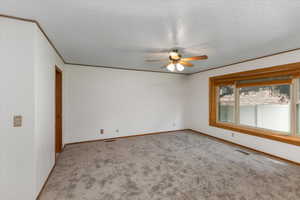 Carpeted empty room with a textured ceiling and ceiling fan