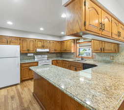 Kitchen with sink, light hardwood / wood-style flooring, white appliances, and tasteful backsplash