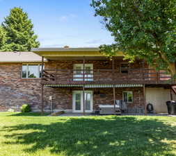 Rear view of house featuring a balcony and a lawn