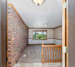 Interior space featuring ornamental molding, a textured ceiling, and brick wall