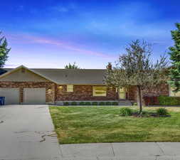 Ranch-style house with a garage and a lawn