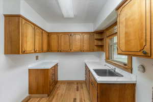 Kitchen featuring sink, a textured ceiling, and light wood-type flooring