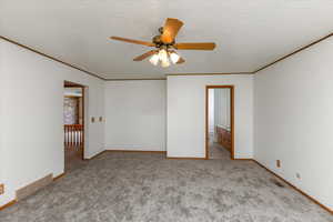 Carpeted spare room with a textured ceiling, ornamental molding, and ceiling fan