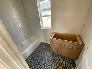 Bathroom with tile patterned floors, a washtub, and a wealth of natural light