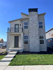 View of front of house featuring a balcony and a front lawn