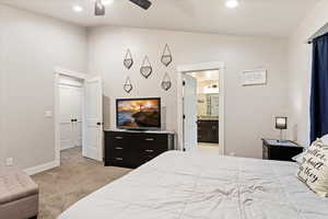 Carpeted bedroom with lofted ceiling, ensuite bathroom, and ceiling fan