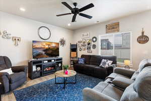 Living room with ceiling fan, a fireplace, and hardwood / wood-style flooring