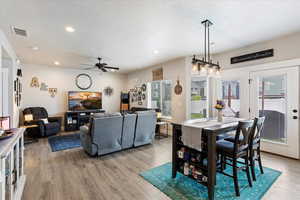 Dining room with ceiling fan, light hardwood / wood-style floors, and a textured ceiling