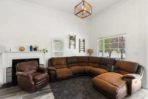 Living room with wood-type flooring, a chandelier, and crown molding