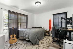 Bedroom with a textured ceiling, crown molding, and hardwood / wood-style flooring