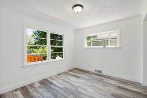 Spare room featuring plenty of natural light, light hardwood / wood-style floors, and a textured ceiling