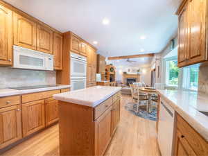 Kitchen with a kitchen island, ceiling fan, light hardwood / wood-style flooring, and white appliances