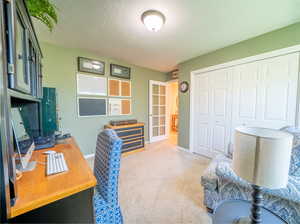 Office with a textured ceiling, carpet flooring, and french doors