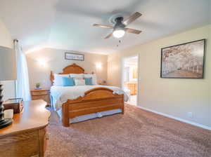 Bedroom with ceiling fan, ensuite bathroom, lofted ceiling, and carpet