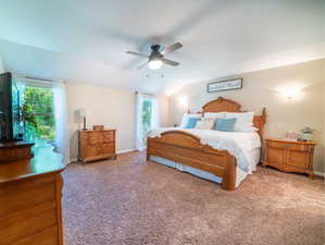 Carpeted bedroom with lofted ceiling, ceiling fan, and multiple windows