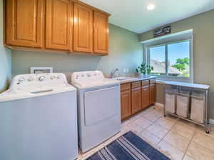 Laundry room with cabinets, separate washer and dryer, hookup for a washing machine, sink, and light tile floors