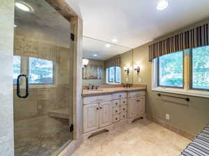 Bathroom with a healthy amount of sunlight, tile flooring, dual vanity, and a shower with shower door