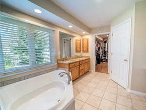 Bathroom featuring tile flooring, tiled tub, and vanity