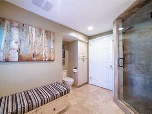 Bathroom with a shower with shower door, tile flooring, and toilet