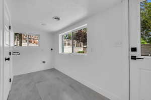 Tiled empty room featuring a textured ceiling