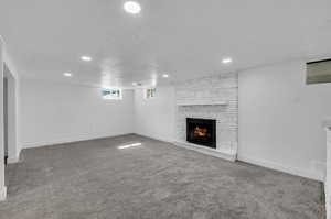 Unfurnished living room with a textured ceiling, carpet floors, and a fireplace